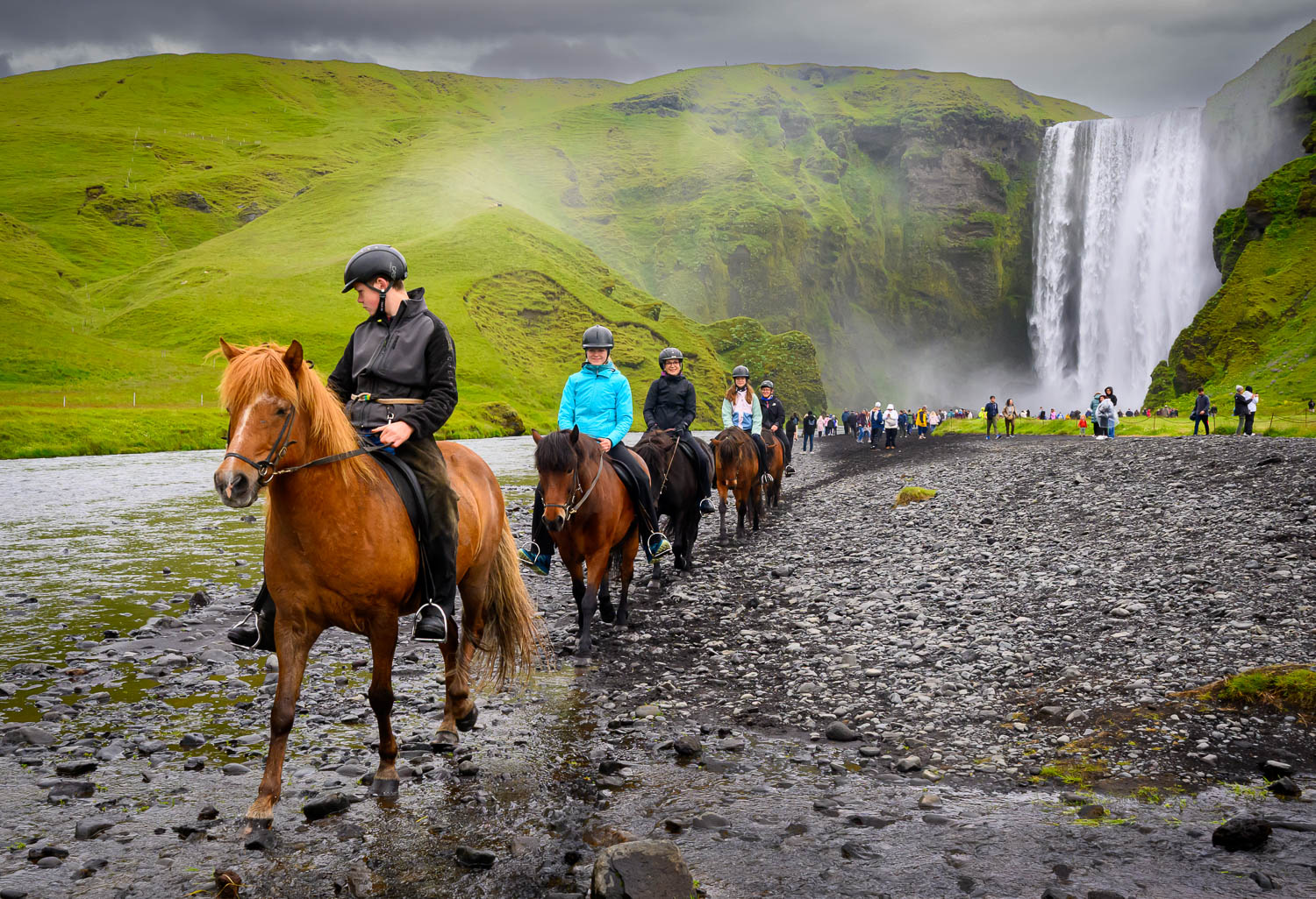 people on horses riding near big waterfall